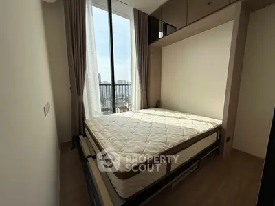 Modern bedroom with large window and city view, featuring a comfortable bed and elegant curtains.