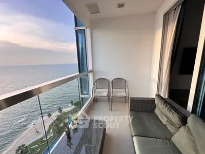 Stunning ocean view from modern balcony with cozy seating area.