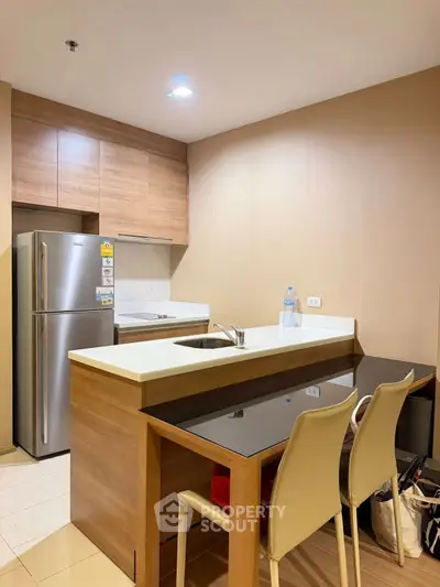 Modern kitchen with sleek design, featuring stainless steel fridge and stylish dining area.
