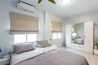 Spacious bedroom with modern decor and ample natural light, featuring a comfortable bed and stylish wardrobe.