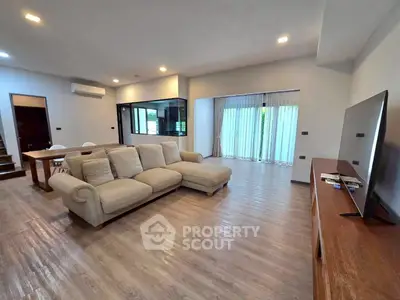 Spacious modern living room with elegant sofa and large TV, perfect for relaxation and entertainment.