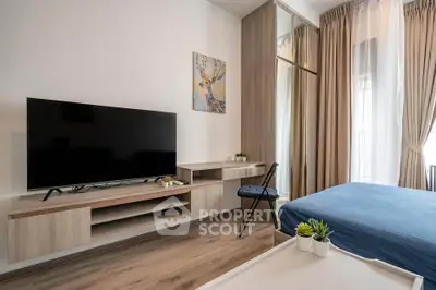 Modern bedroom with stylish decor and large TV, featuring floor-to-ceiling curtains and wooden flooring.