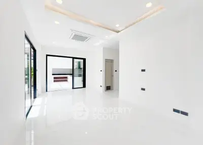 Spacious modern living room with sleek white interior and large windows for natural light.