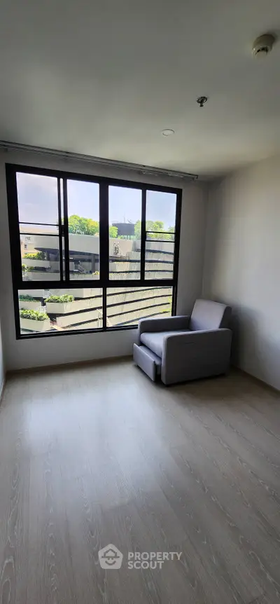 Spacious room with large window and modern armchair, offering a serene view.