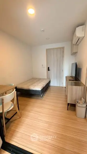 Cozy studio apartment with modern furnishings and wooden flooring, featuring a compact living space ideal for urban living.