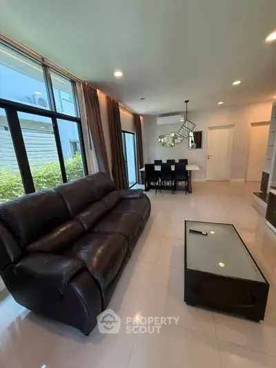 Spacious living room with modern leather sofa and dining area
