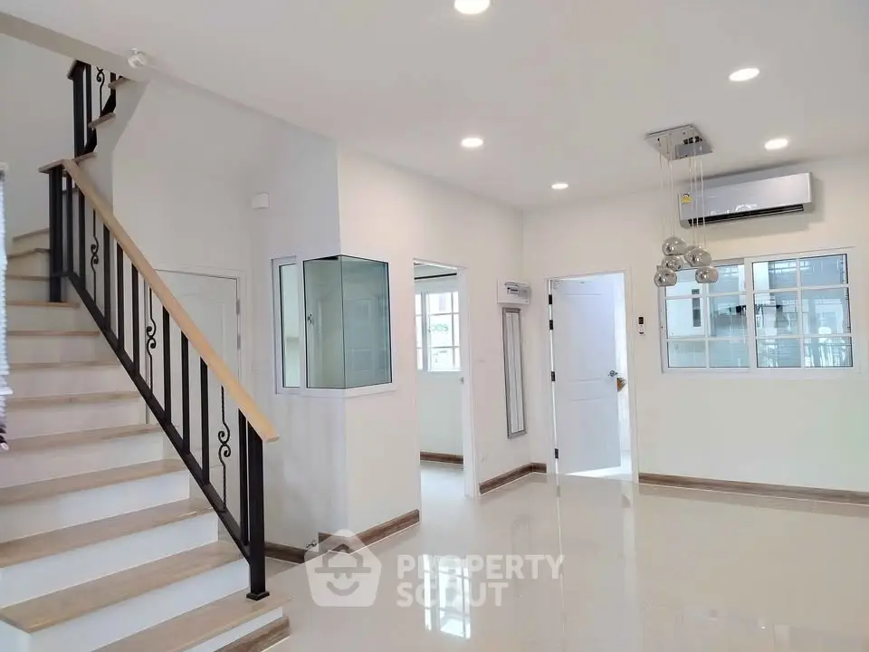 Spacious modern living room with staircase and elegant lighting in a contemporary home.