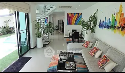 Modern living room with vibrant decor and poolside view, featuring stylish furniture and colorful artwork.