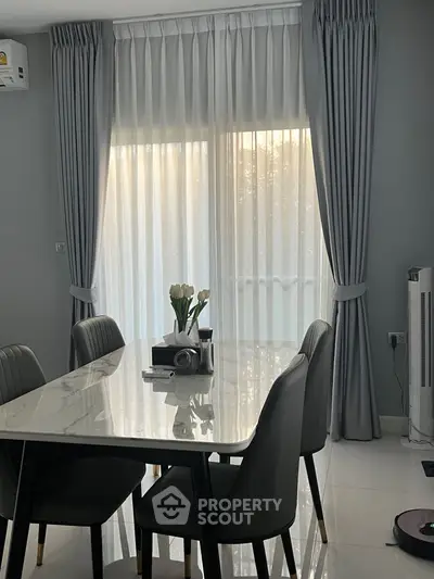 Elegant dining area with marble table and modern chairs, featuring floor-to-ceiling windows with sheer curtains.