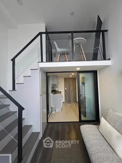 Modern loft apartment with sleek staircase and open living area, featuring stylish furniture and contemporary design.