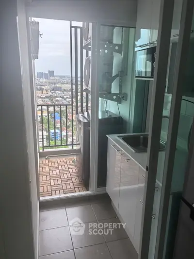 Compact kitchen with balcony offering stunning city view, featuring modern appliances and sleek design.