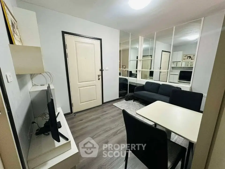 Modern living room with sleek furniture and mirrored wall for spacious feel.