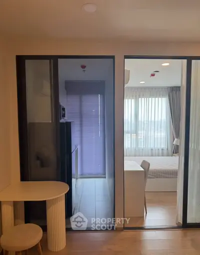 Modern apartment interior with bedroom and dining area, featuring large windows and sleek design.