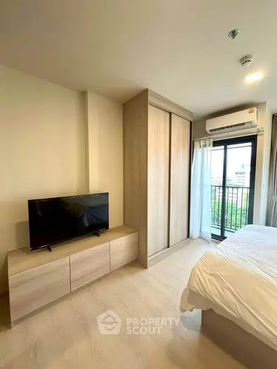 Modern bedroom with TV, wardrobe, and balcony view in a stylish apartment.