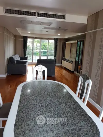 Spacious living room with elegant decor and large windows offering a serene garden view.