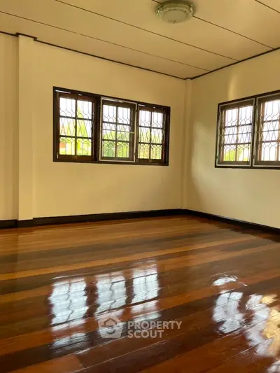 Spacious empty room with polished wooden floors and large windows