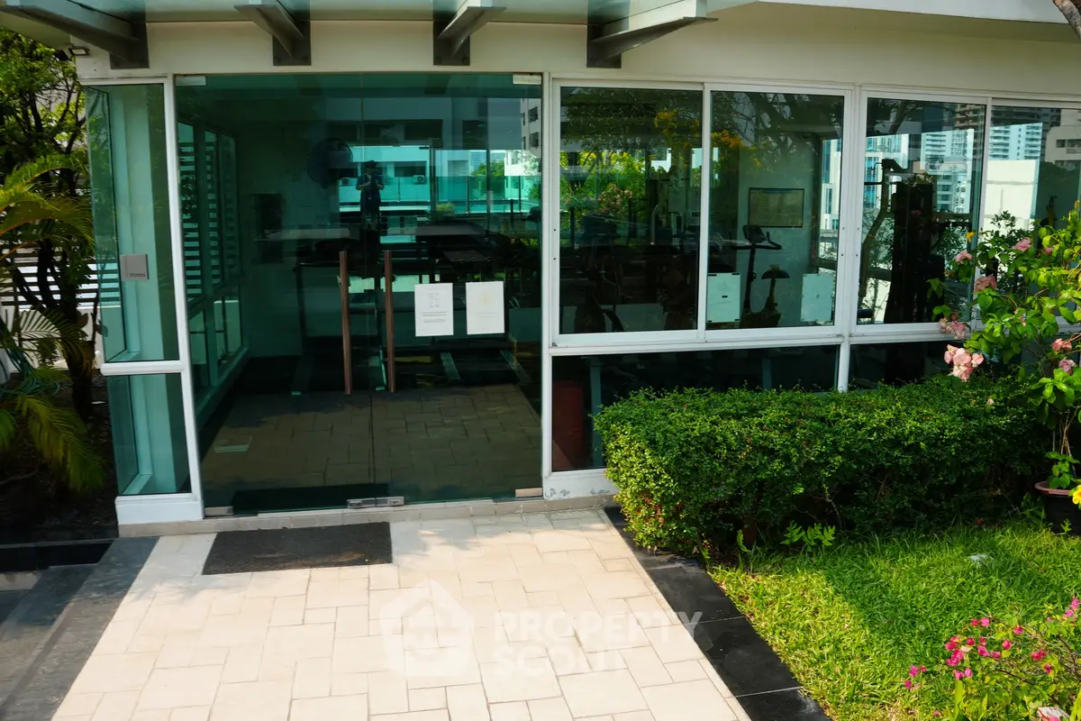 Modern gym exterior with glass walls and lush greenery in a luxury residential building.