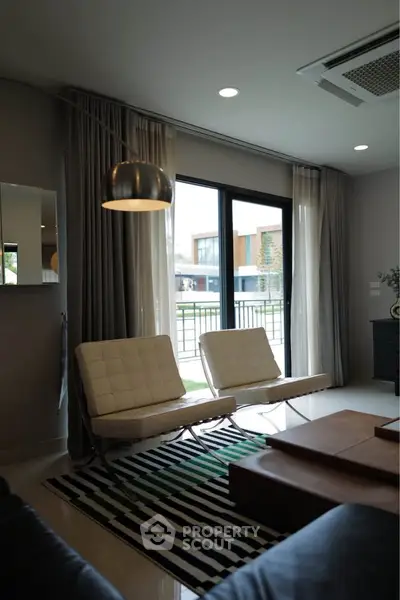Modern living room with stylish furniture and large window offering a view of contemporary architecture.