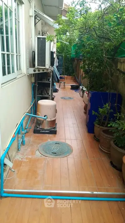 Charming outdoor corridor with potted plants and utility area, perfect for gardening enthusiasts.