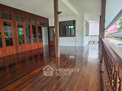 Spacious wooden balcony with elegant railing and large windows, perfect for outdoor relaxation.
