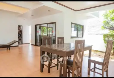 Spacious open-plan dining area with wooden furniture and large windows in a modern home.