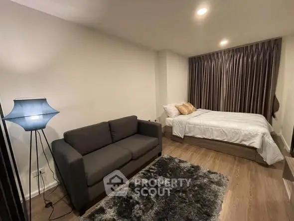 Cozy bedroom with modern decor, featuring a plush sofa and elegant lighting, perfect for relaxation.