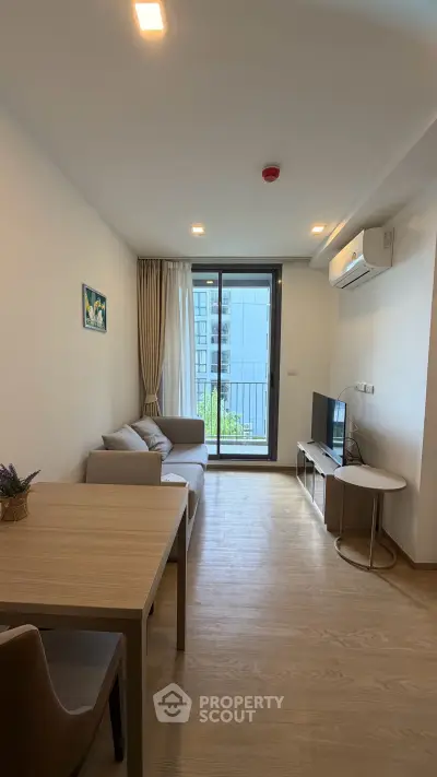 Modern living room with balcony view, featuring sleek furniture and natural light.