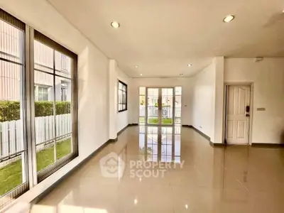 Spacious and bright living room with large windows and glossy tiled floors.