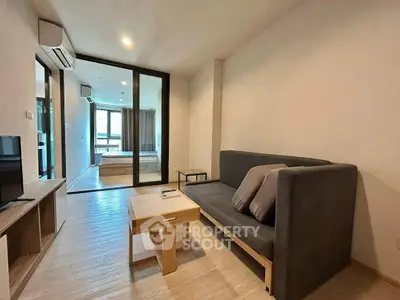 Modern living room with sleek furniture and open view into bedroom, perfect for urban living.