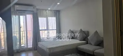 Modern bedroom with large windows and balcony access in a high-rise apartment.
