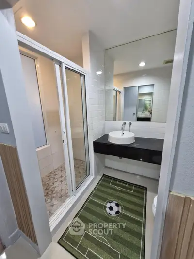 Modern bathroom with glass shower and unique soccer-themed rug