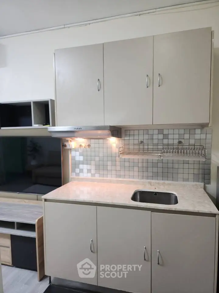 Compact kitchen with modern cabinetry and tiled backsplash, ideal for efficient cooking in small spaces.