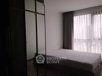 Modern bedroom with large window and mirrored wardrobe in urban apartment