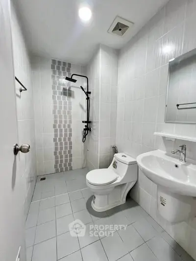 Modern bathroom with sleek fixtures and minimalist design, featuring a walk-in shower and contemporary tiles.