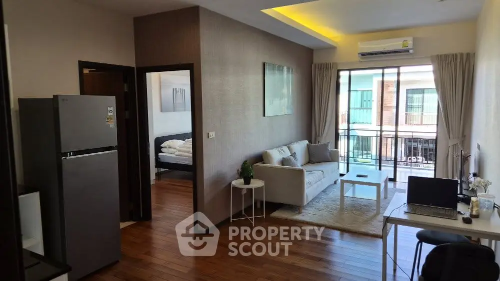 Modern living room with balcony view, featuring sleek furniture and wooden flooring in a stylish apartment.