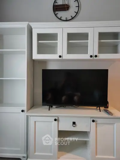 Modern living room with sleek white cabinetry and flat-screen TV, perfect for stylish entertainment setup.