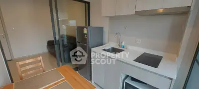 Modern kitchen with sleek cabinetry and dining area in a contemporary apartment.
