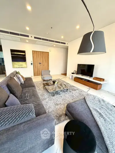 Luxurious modern living room with plush gray sofas, stylish decor, and a sleek entertainment center.