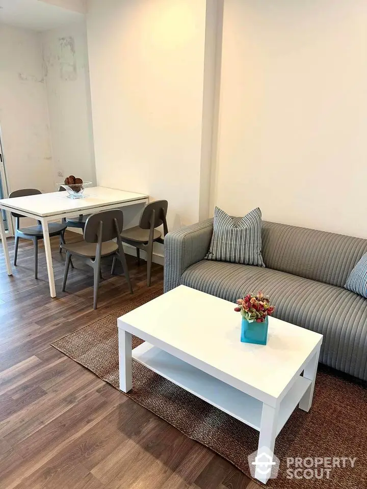 Modern living room with stylish furniture and dining area, featuring hardwood floors and cozy decor.