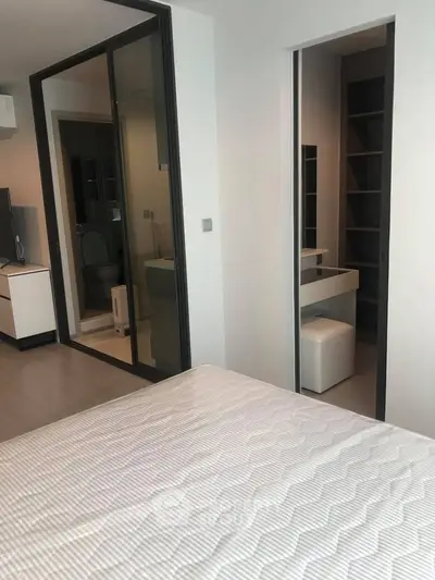 Modern bedroom with ensuite bathroom and walk-in closet, featuring sleek design and ample storage space.