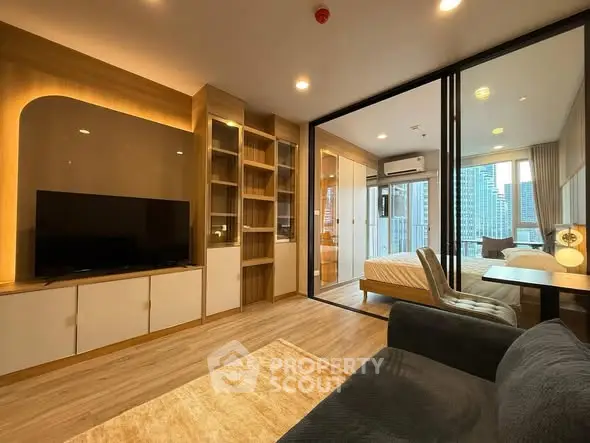 Modern living room with glass partition leading to a stylish bedroom and city view.