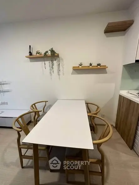 Modern dining area with sleek table and stylish chairs, featuring minimalist decor and wall-mounted shelves.
