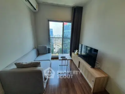 Modern living room with city view, featuring sleek furniture and large window for natural light.