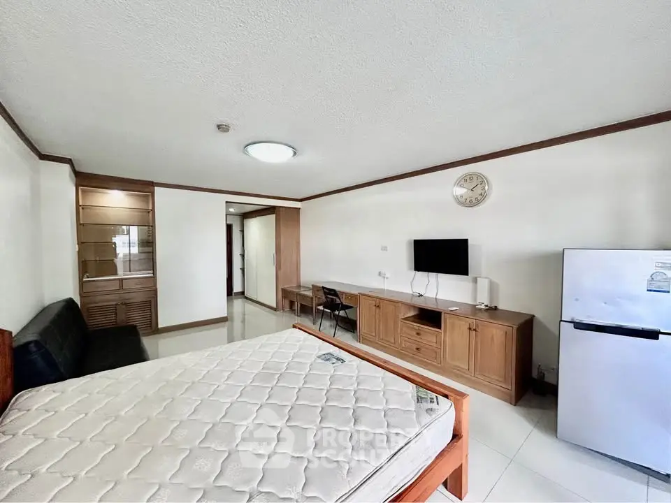 Spacious studio apartment with modern furnishings and ample natural light, featuring a cozy living area and functional kitchen.