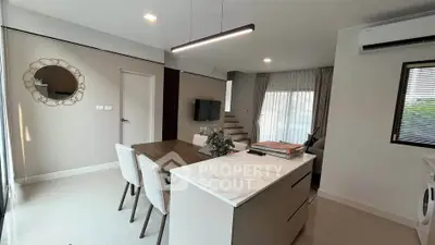Modern open-plan living room with dining area and sleek kitchen island in a stylish home.