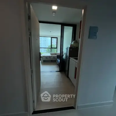 Cozy apartment entrance leading to a bright bedroom with large windows and a compact kitchen area.