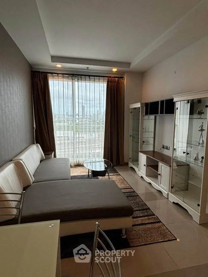 Modern living room with sleek furniture and large window offering city views.