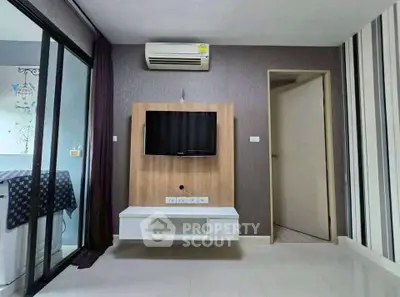 Modern living room with wall-mounted TV and air conditioning in stylish apartment.