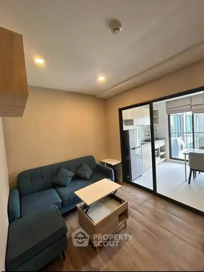 Modern living room with stylish furniture and open layout leading to a bright kitchen area.