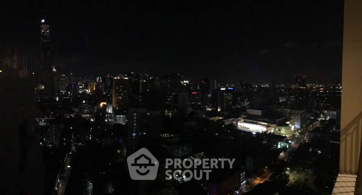 Stunning city skyline view from a high-rise balcony at night, showcasing vibrant urban lights.